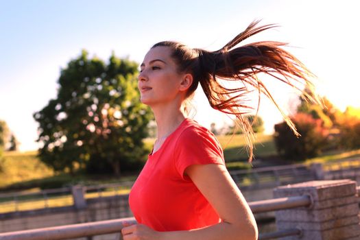 Beautiful young woman in sports clothing running while exercising outdoors