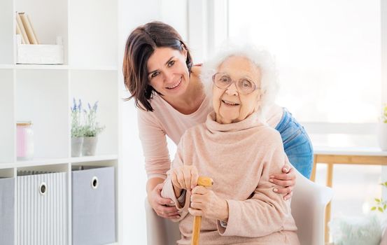 Happy elderly woman embraced by daughter at home