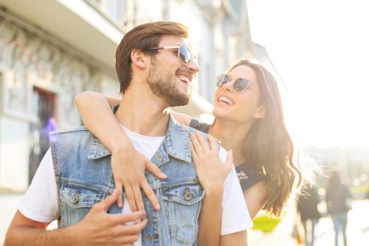 Beautiful young couple in love walking outdoors at the city street, hugging