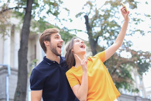 Beautiful lovely young couple walking at the city streets, taking a selfie