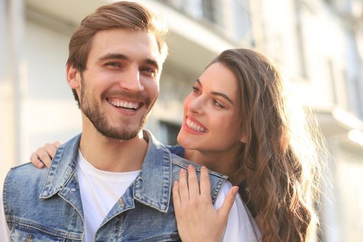 Beautiful young couple in love walking outdoors at the city street, hugging