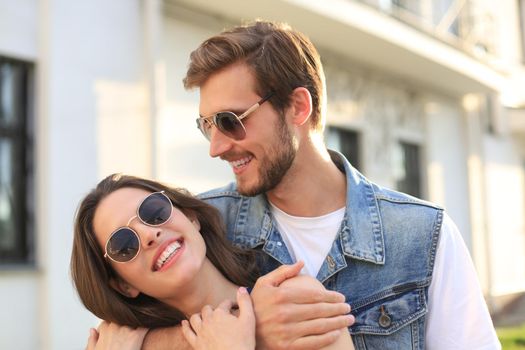 Beautiful young couple in love walking outdoors at the city street, hugging