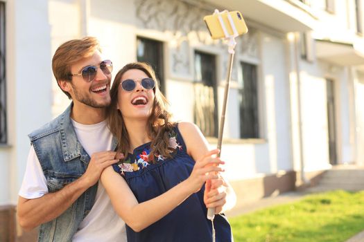 Beautiful lovely young couple walking at the city streets, hugging while taking a selfie