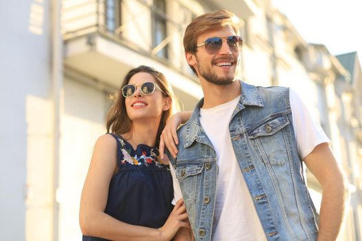 Beautiful young couple in love walking outdoors at the city street, hugging