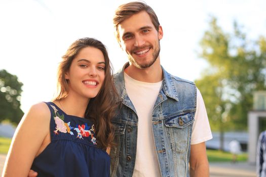 Image of lovely happy couple in summer clothes smiling and holding hands together while walking through city street