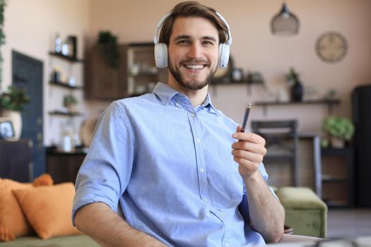 Happy young man in earphones working from home during self isolation