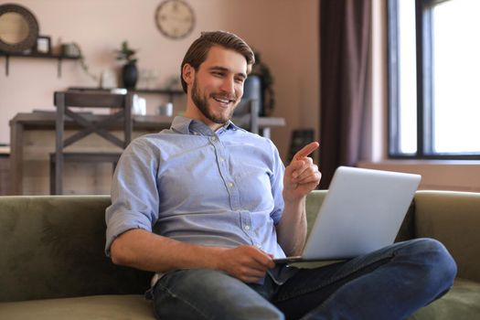 Smiling businessman greeting colleagues in video conference and negotiating distantly from home