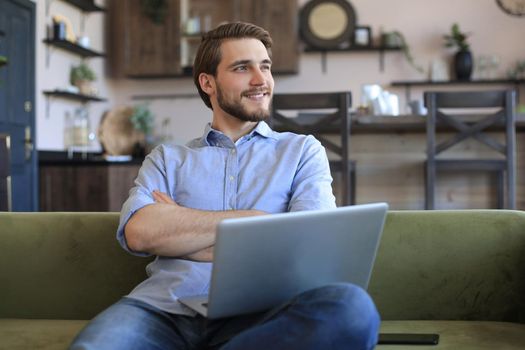 Smiling businessman greeting colleagues in video conference and negotiating distantly from home