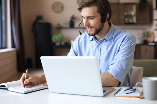 Confident man wearing headset speaking and watching business webinar training, listening to lecture
