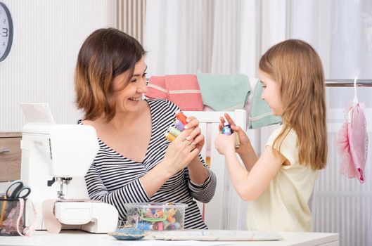 Smiling sewing team choosing with which color thread to work