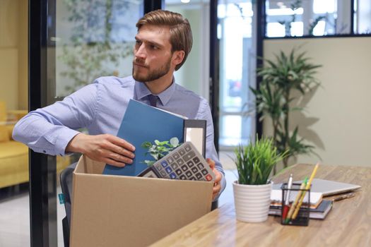 Sad dismissed worker are taking his office supplies with him from office