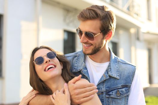 Beautiful young couple in love walking outdoors at the city street, hugging