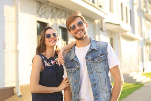 Beautiful young couple in love walking outdoors at the city street, hugging