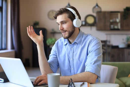 Confident man wearing headset speaking and watching business webinar training, listening to lecture