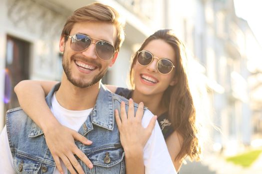 Beautiful young couple in love walking outdoors at the city street, hugging