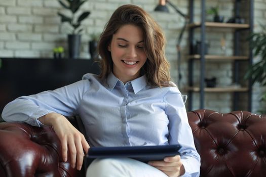Young smiling woman with tablet pc on the sofa