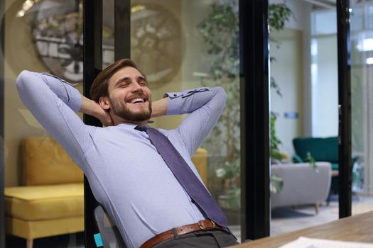 Smiling handsome businessman relaxing in a modern office