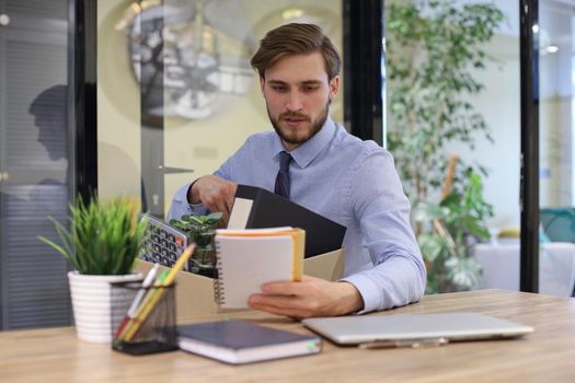 Sad dismissed worker are taking his office supplies with him from office