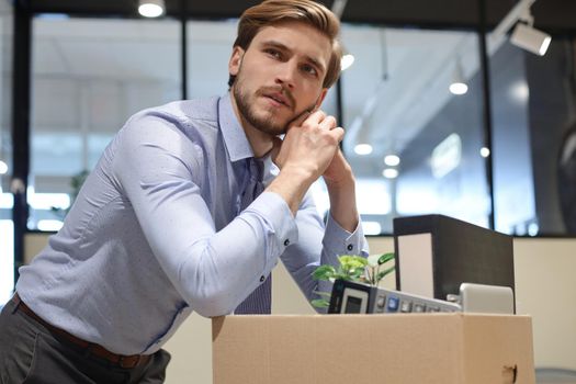 Sad dismissed worker are taking his office supplies with him from office