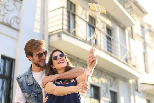 Beautiful lovely young couple walking at the city streets, hugging while taking a selfie