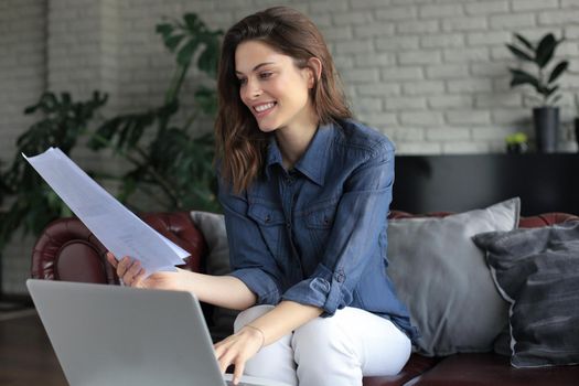Smiling girl sit on couch watching webinar on laptop. Happy young woman study on online distant course