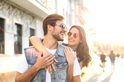 Beautiful young couple in love walking outdoors at the city street, hugging