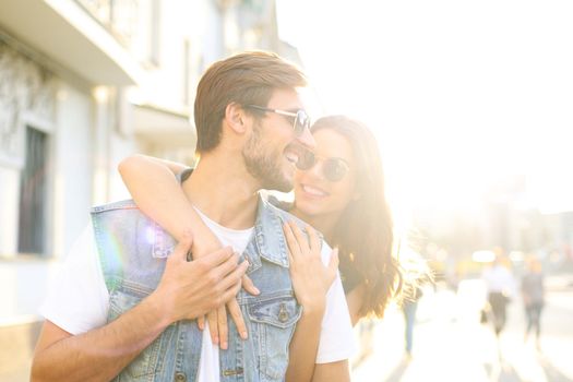 Beautiful young couple in love walking outdoors at the city street, hugging