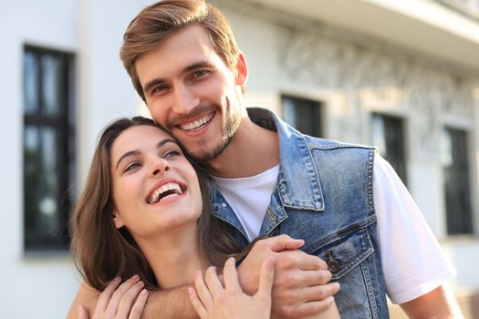 Beautiful young couple in love walking outdoors at the city street, hugging