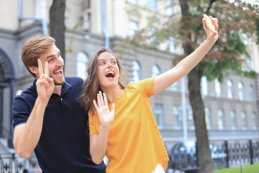 Beautiful lovely young couple walking at the city streets, taking a selfie