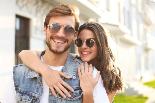 Beautiful young couple in love walking outdoors at the city street, hugging