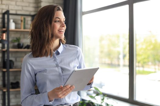 Attractive smiling woman working on a tablet in a home office
