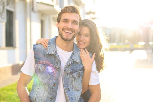 Beautiful young couple in love walking outdoors at the city street, hugging