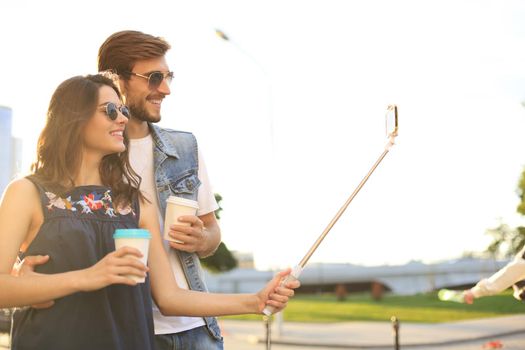 Beautiful lovely young couple walking at the city streets, hugging while taking a selfie