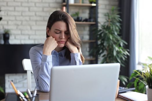 Tired young girl student sitting at table, leaning head on hand, napping during break pause time at home