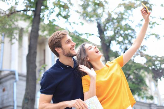 Beautiful lovely young couple walking at the city streets, taking a selfie