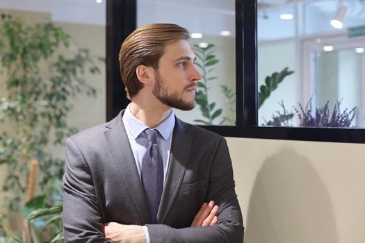 Portrait of happy businessman with arms crossed standing in office