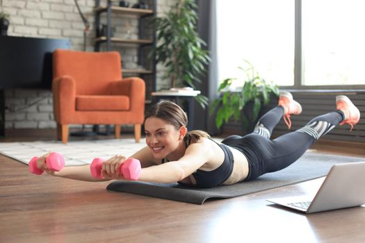 Young beautiful sports girl in leggings and a top does exercises with dumbbells. Healthy lifestyle. A woman goes in for sports at home