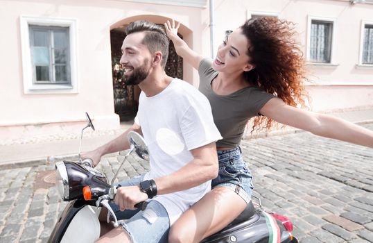 Happy cheerful couple riding vintage scooter outdoors.