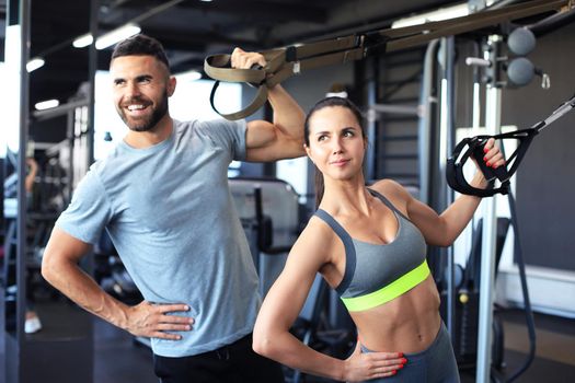 Young couple on body training with trx in gym
