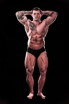 in full growth. handsome male bodybuilder showing his muscles.isolated on black background