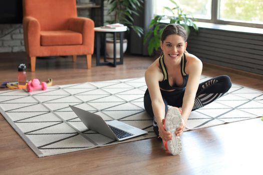 Fitness beautiful slim woman doing fitness stretching exercises at home in the living room. Stay at home activities. Sport, healthy lifestyle