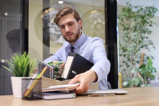 Sad dismissed worker are taking his office supplies with him from office