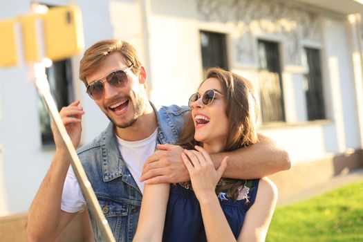 Beautiful lovely young couple walking at the city streets, hugging while taking a selfie