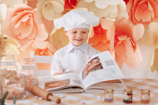 happy boy chef chooses a cooking recipe. the concept of a hobby