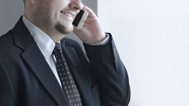 handsome pensive businessman using smartphoone and looking through window in the office.photo with copy space