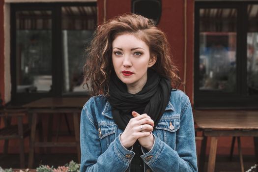 beautiful young woman in denim jacket standing near street cafe