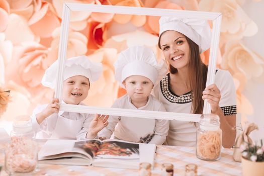 photo happy mom with children in the kitchen standing in front of the table . the concept of parenting