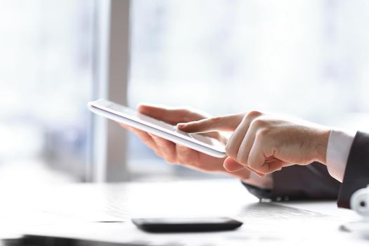 close up.businessman tapping the screen of the digital tablet.photo on blurred background