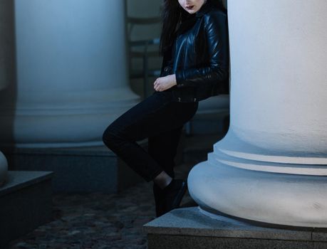 stylish young woman standing near a pillar of a city building . city life