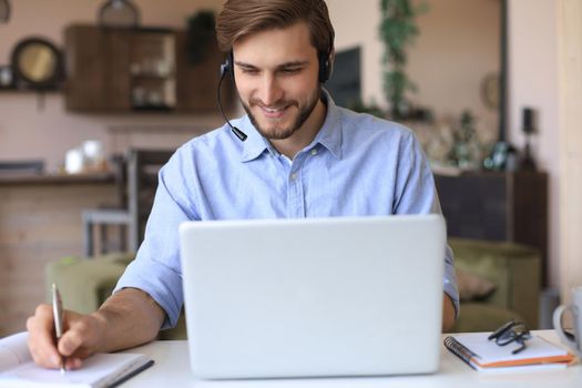 Confident man wearing headset speaking and watching business webinar training, listening to lecture